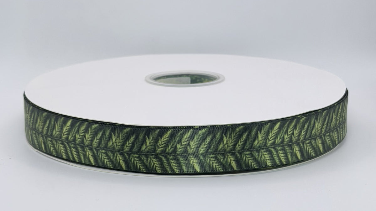 Fern ribbon with light green fern fronds on a deep green background, shown on a white spool.