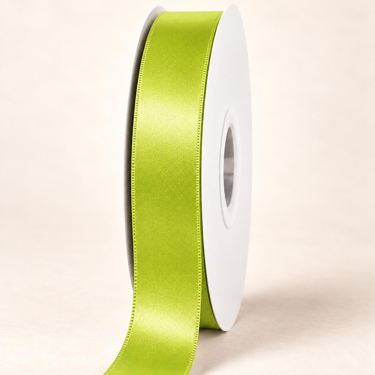 Apple Green — 22 mm satin ribbon on a white roll against an ivory background