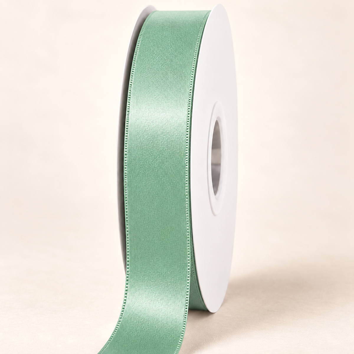 Celedon — 22 mm satin ribbon on a white roll against an ivory background