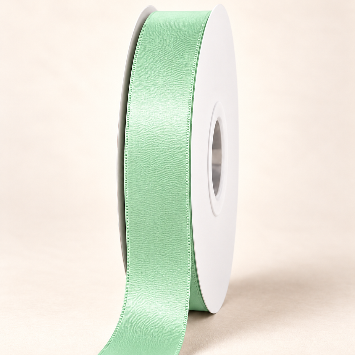 Mint — 22 mm satin ribbon on a white roll against an ivory background