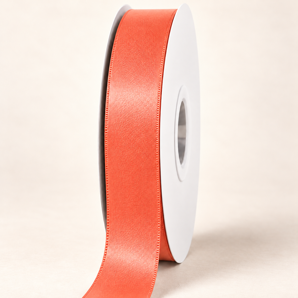 Neon Orange — 22 mm satin ribbon on a white roll against an ivory background