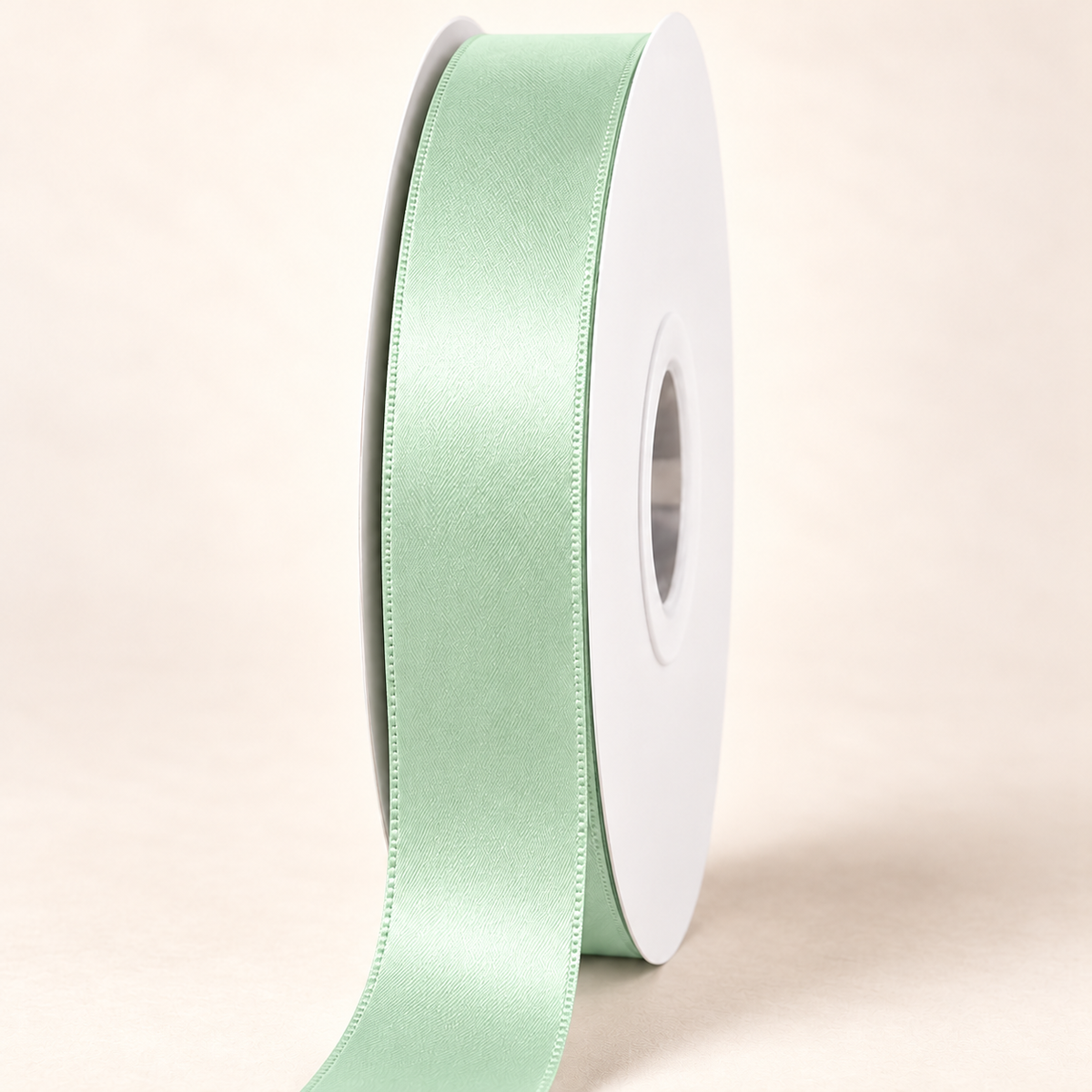 Pastel Green — 22 mm satin ribbon on a white roll against an ivory background