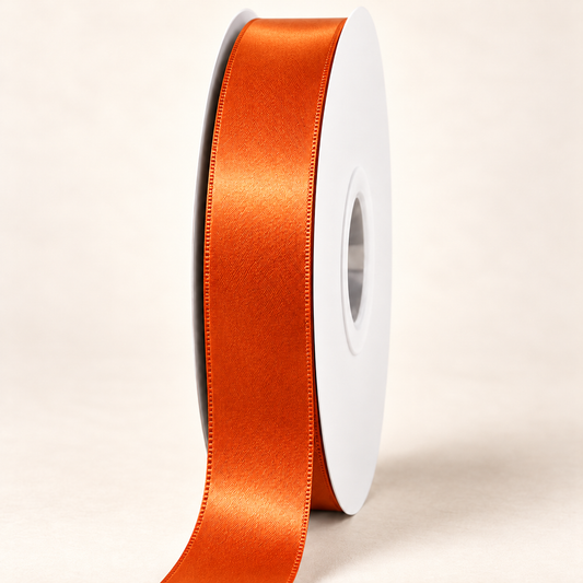 Russet Orange — 22 mm satin ribbon on a white roll against an ivory background